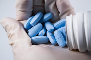 blue pills in gloved hands