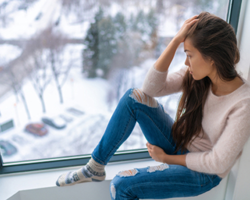 woman-with-sad-looks-out-window-to-wintery-day