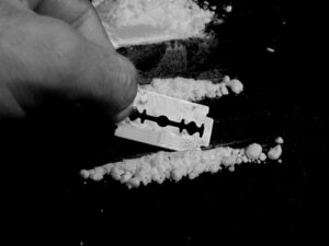 Cocaine being cut by a razor in black and white