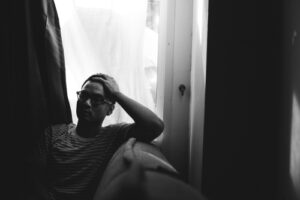 Man sitting by a window in black and white