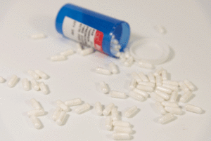 White capsule pills spilling out of a blue container