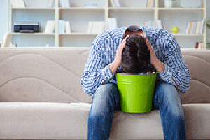 Man puking into a green bucket