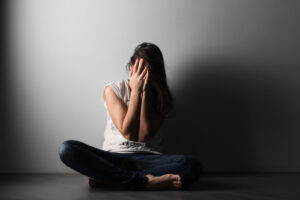 Stressed woman covering her face and sitting on the floor