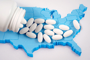 White pills spilled over a blue 3D model of the United States