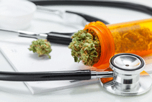 Marijuana in a prescription bottle around papers and a stethoscope on a table