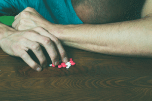 Man with his head on a counter with pills by his hands