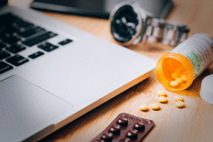 Pills strewn about next to a laptop
