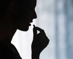 Silhouette of a woman eating a pill