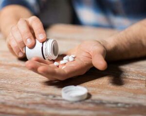 Man pouring pills from a white bottle into his palm