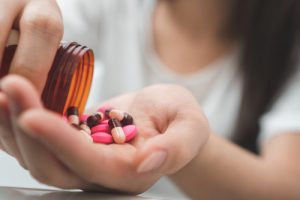 A girl pouring pink pills into her hand