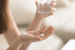 A woman with a glass of water and a pill in her hands